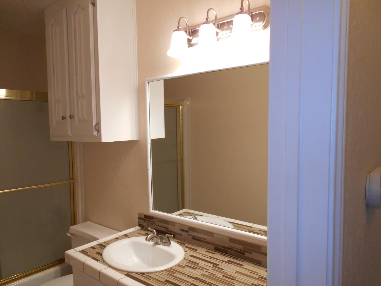 5739 Emory Street Lubbock, TX 79416 - Photo 12 of 14 a bathroom with a sink and a mirror