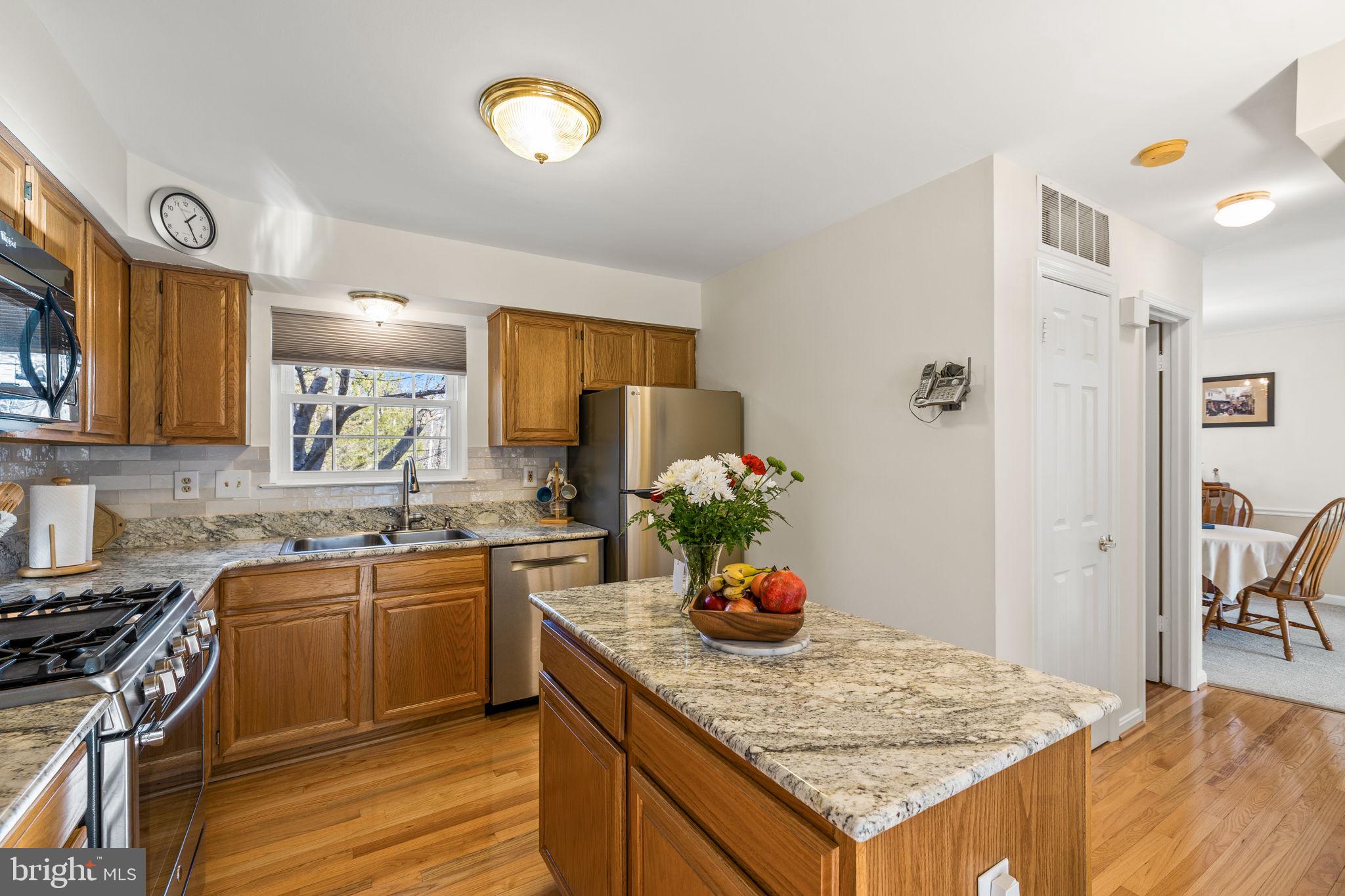 13911 Ruler Court Woodbridge, VA 22193 - Photo 11 of 38 a kitchen with granite countertop a sink cabinets and wooden floor