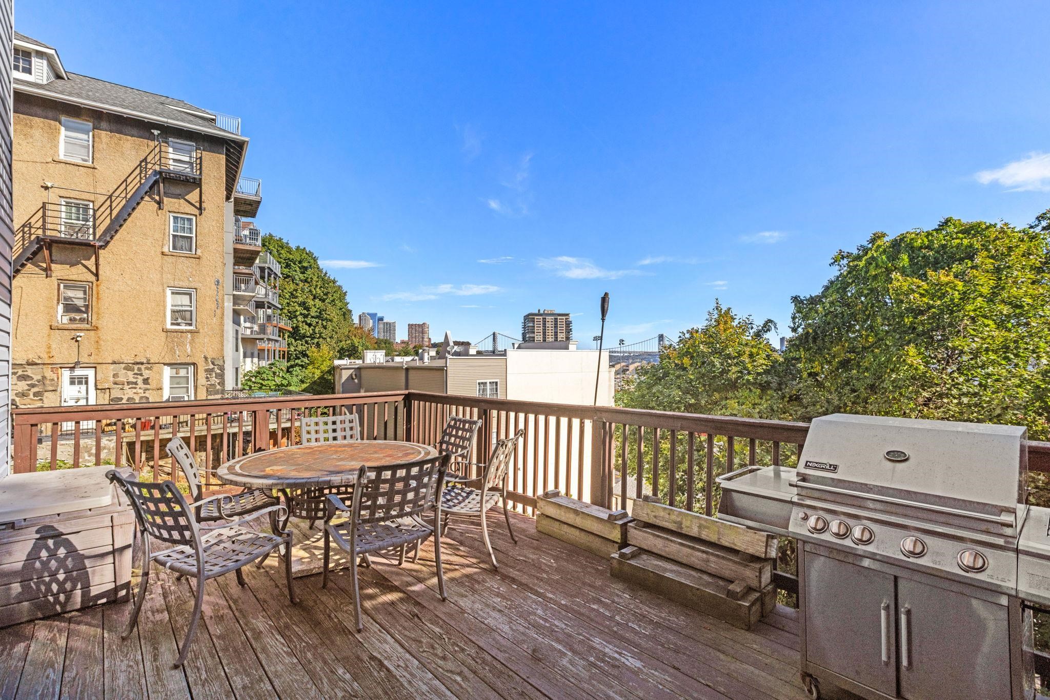 67 Highway 5 Edgewater, NJ 07020 - Photo 12 of 23 a view of a roof deck with table and chairs with wooden floor and fence