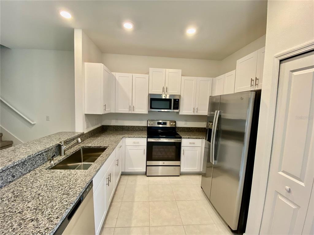 10373 Lavender Aster Trail San Antonio, FL 33576 - Photo 10 of 34 a kitchen with granite countertop stainless steel appliances a refrigerator a stove a sink and a counter top