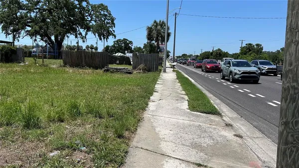 a view of a garden with a bench and trees in the background
