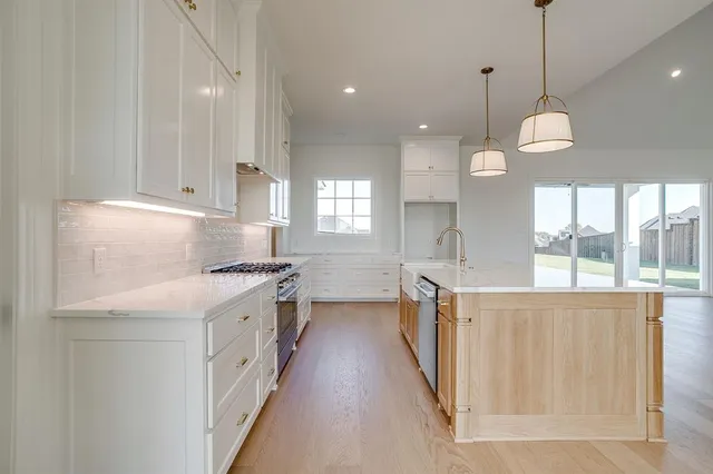 a kitchen with stainless steel appliances granite countertop a sink a stove and a wooden floors