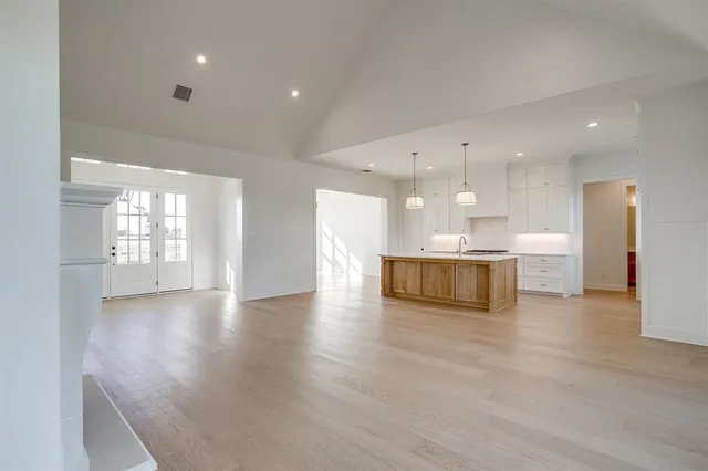 a view of an empty room and kitchen with kitchen island white cabinetry