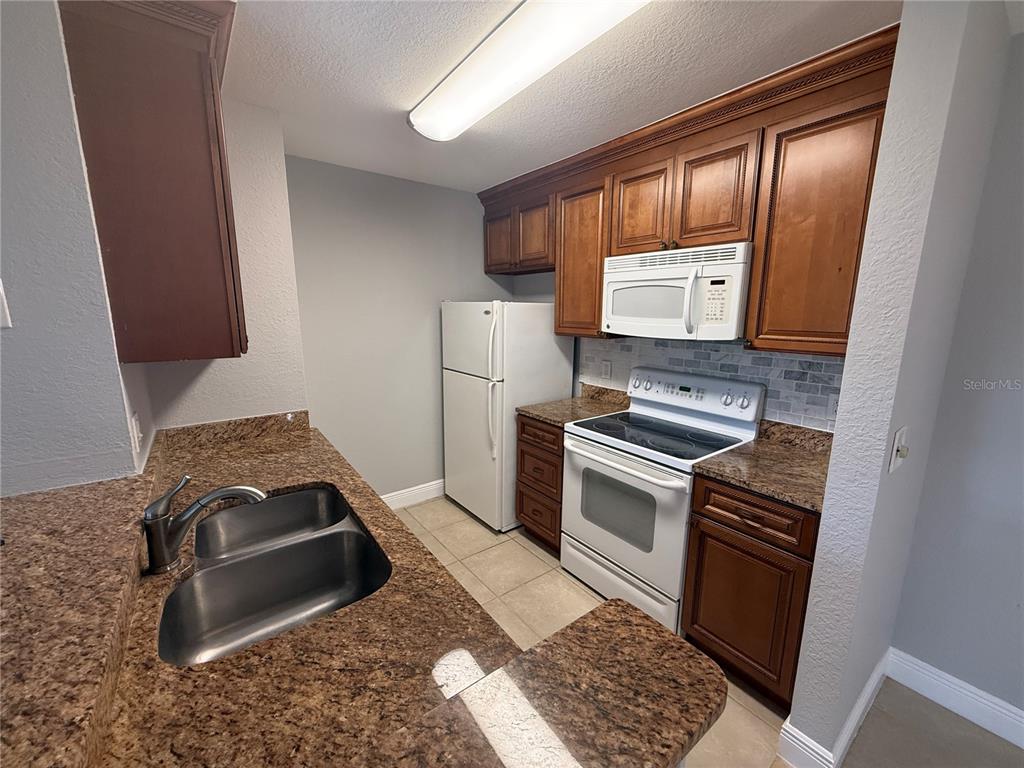 8932 Manor Loop, Unit 205 Lakewood Ranch, FL 34202 - Photo 14 of 15 a kitchen with stainless steel appliances granite countertop a stove and a refrigerator