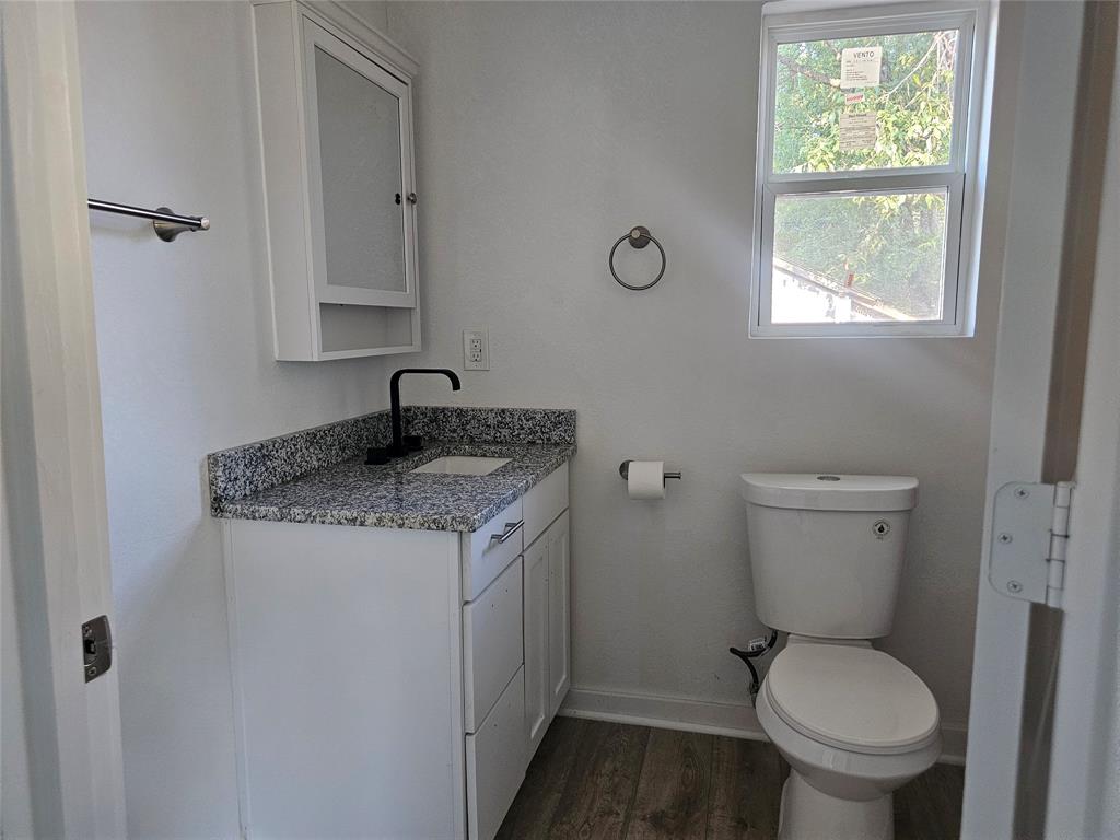 2426 South Tyler Street Dallas, TX 75224 - Photo 14 of 21 a bathroom with a granite countertop toilet a sink and a window