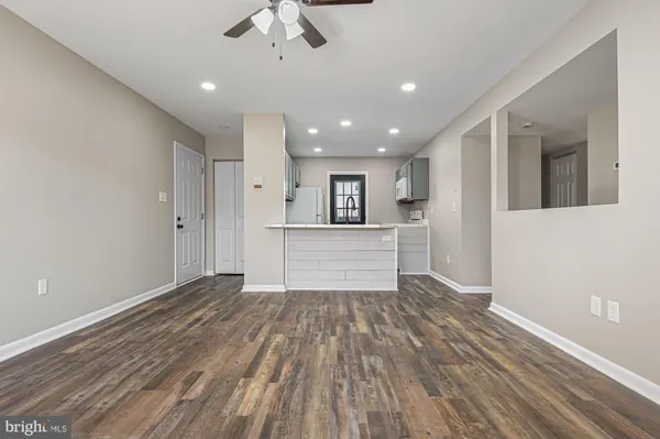 a view of kitchen and empty room with wooden floor