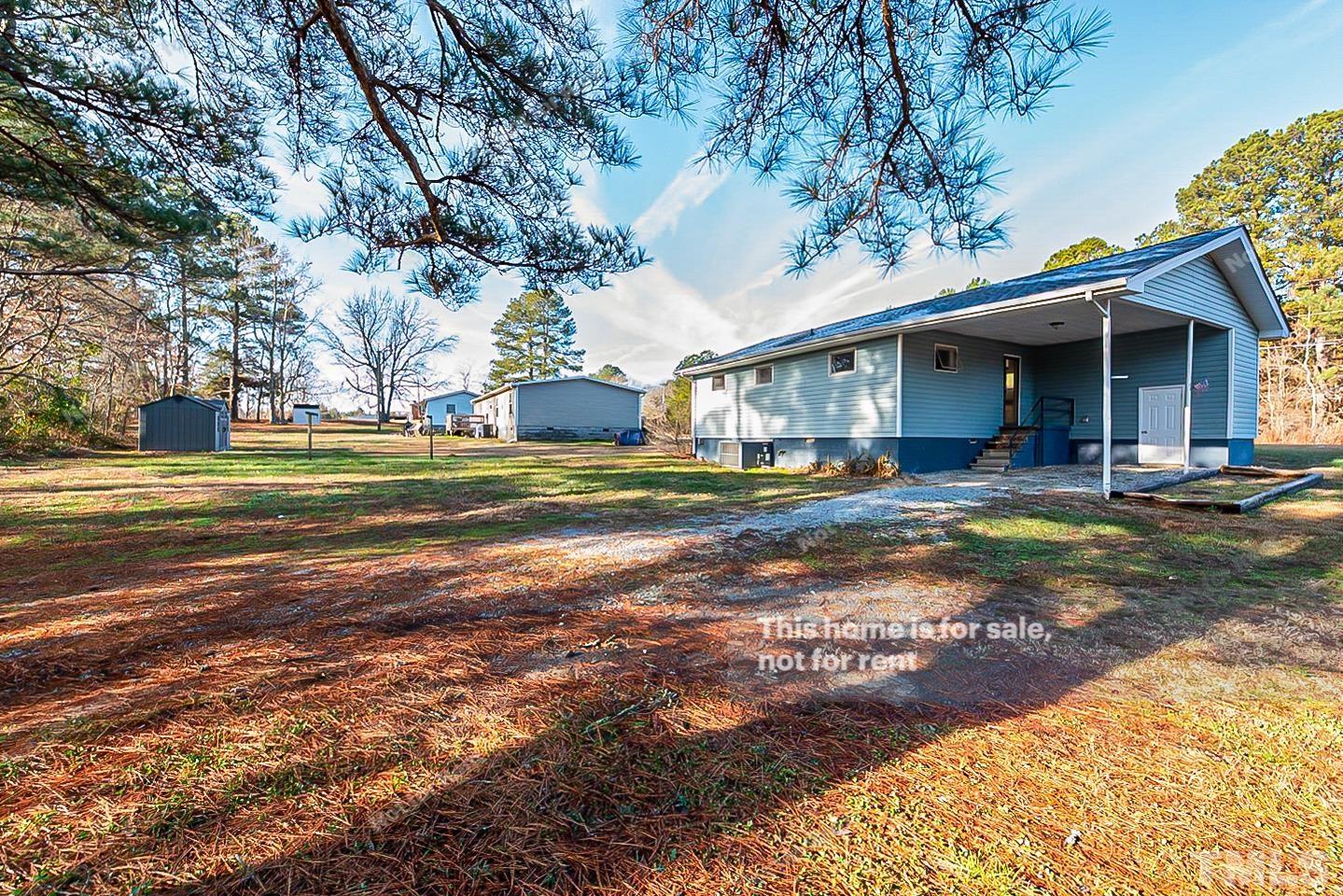 6108 Cheek Road Durham, NC 27704 - Photo 7 of 14 a view of a house with a yard and lawn chairs under an umbrella