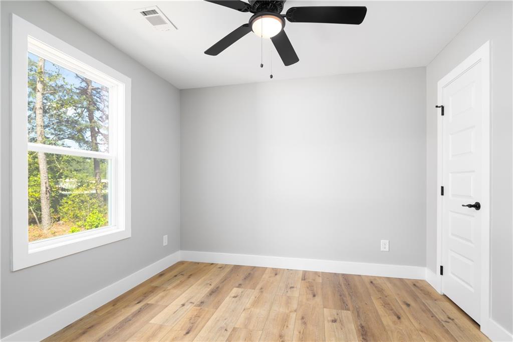 111 Lee Road Phenix City, AL 36867 - Photo 20 of 23 Hardwood-finish flooring, white trim, crisp gray walls, white paneled door with black hardware, and an overhead ceiling fan
