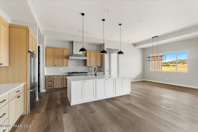 a open kitchen with stainless steel appliances granite countertop a stove a sink dishwasher a refrigerator white cabinets and wooden floor