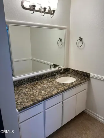 a bathroom with a granite countertop sink and a mirror