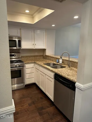 a kitchen with granite countertop a sink stainless steel appliances and cabinets