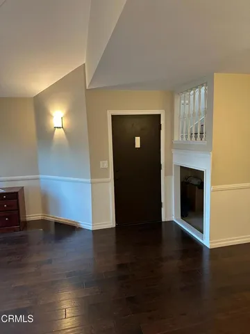 a view of a livingroom with wooden floor and a fireplace