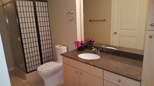 a bathroom with a granite countertop sink mirror vanity and toilet