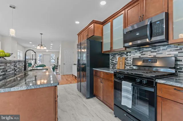 a kitchen with stainless steel appliances granite countertop a stove a sink and a microwave