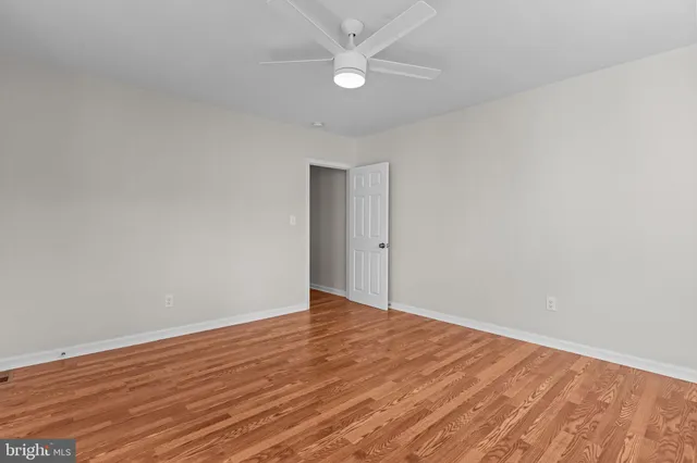 an empty room with wooden floor and fan