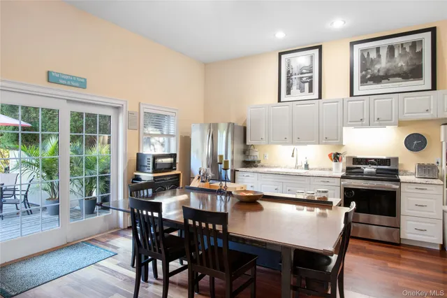 a kitchen with stainless steel appliances granite countertop a stove a refrigerator a kitchen island and chairs in it