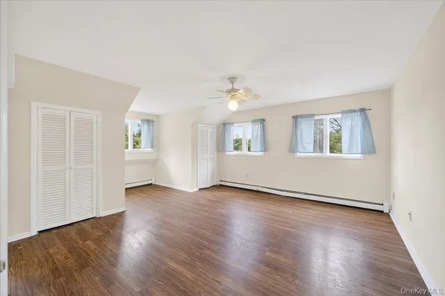 an empty room with wooden floor chandelier fan and windows