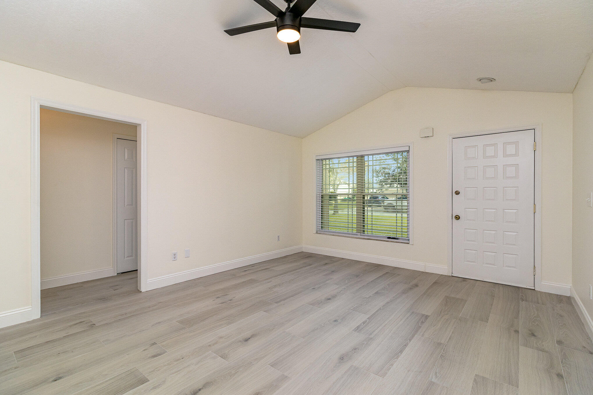 446 Timberlake Drive Melbourne, FL 32940 - Photo 7 of 20 an empty room with wooden floor fan and windows