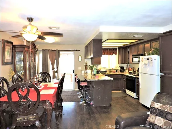 a kitchen with stainless steel appliances kitchen island granite countertop a table chairs in it and a window