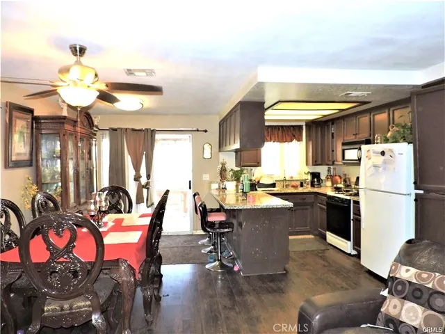 a kitchen with stainless steel appliances kitchen island granite countertop a table chairs in it and a window