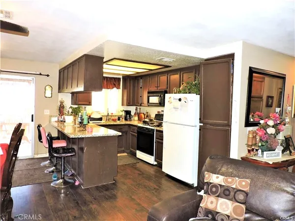 a kitchen with a refrigerator a stove a sink dishwasher and a dining table with wooden floor