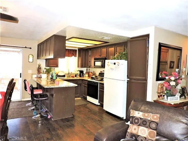 a kitchen with a refrigerator a stove a sink dishwasher and a dining table with wooden floor