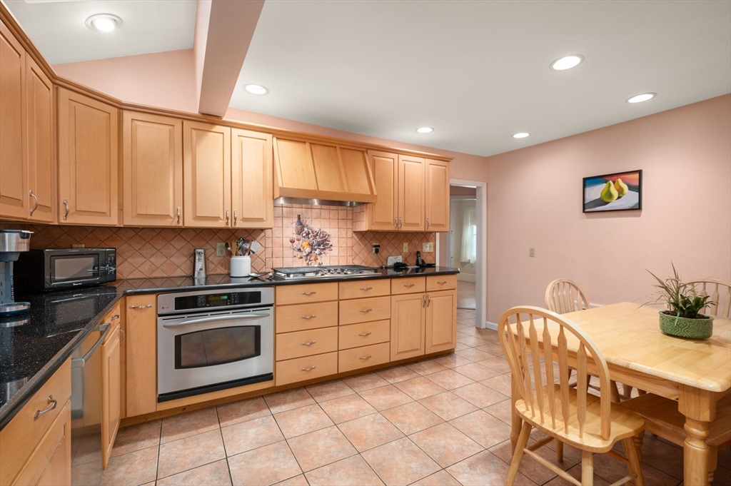 76 Windsor Road, Unit 1 Medford, MA 02155 - Photo 4 of 32 a kitchen with stainless steel appliances granite countertop a stove a sink a microwave a dining table and chairs