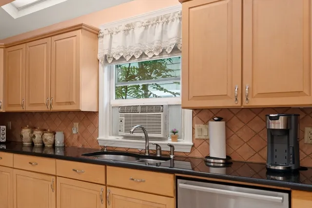 a kitchen with stainless steel appliances granite countertop white cabinets and a window