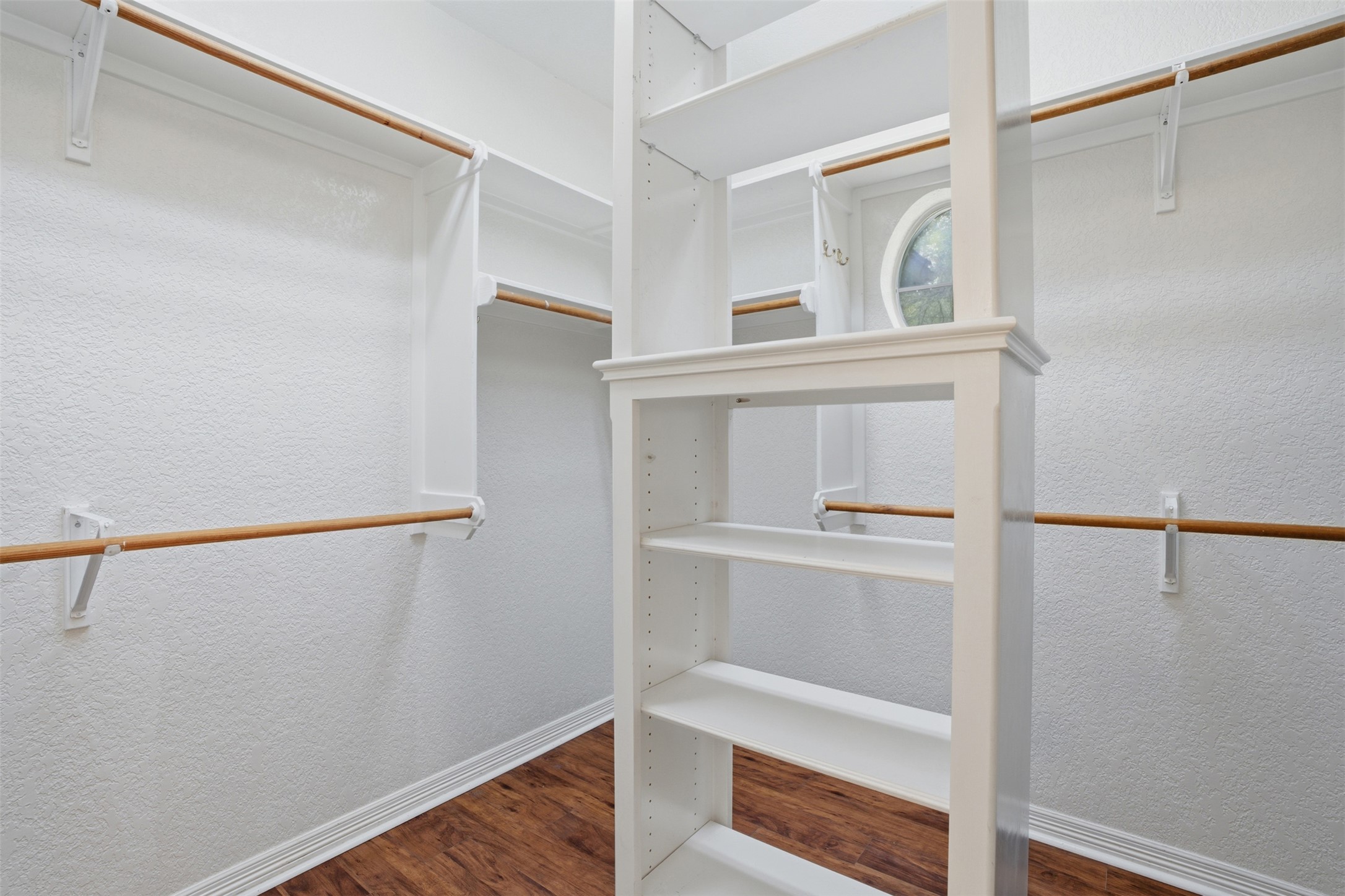 1301 County Road 262 Georgetown, TX 78633 - Photo 21 of 39 Walk-in closet featuring white built-in shelving, multiple hanging rods, and wood-finish flooring