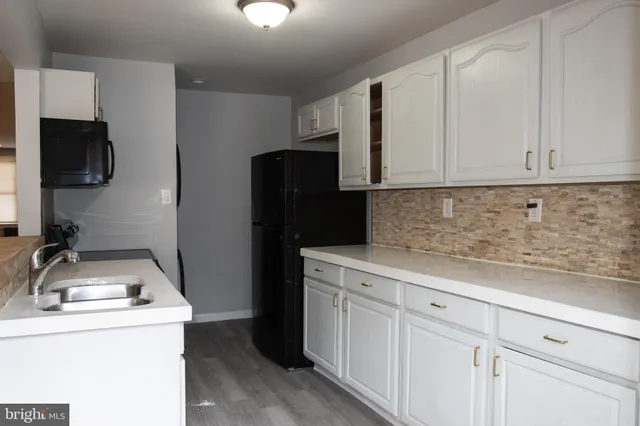 a kitchen with a sink a refrigerator and cabinets