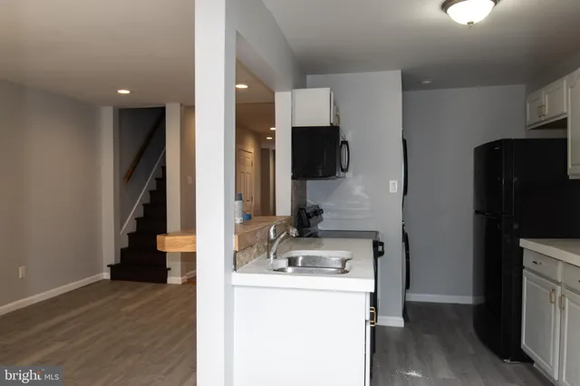 a view of kitchen living space with stainless steel appliances wooden floor and chair