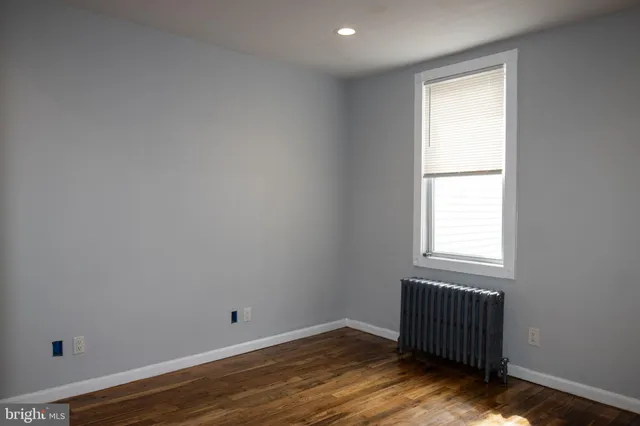 a view of an empty room with closet and wooden floor