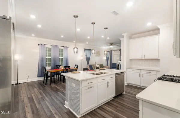 a kitchen with a dining table chairs and white cabinets with wooden floor