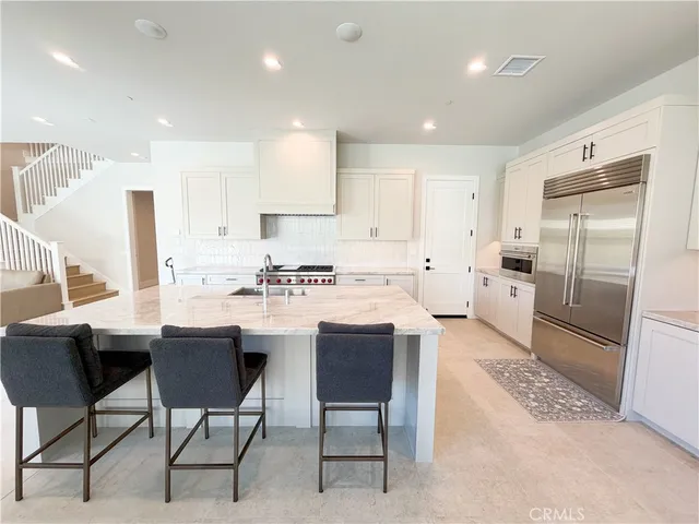 a kitchen with stainless steel appliances kitchen island granite countertop a sink and a refrigerator