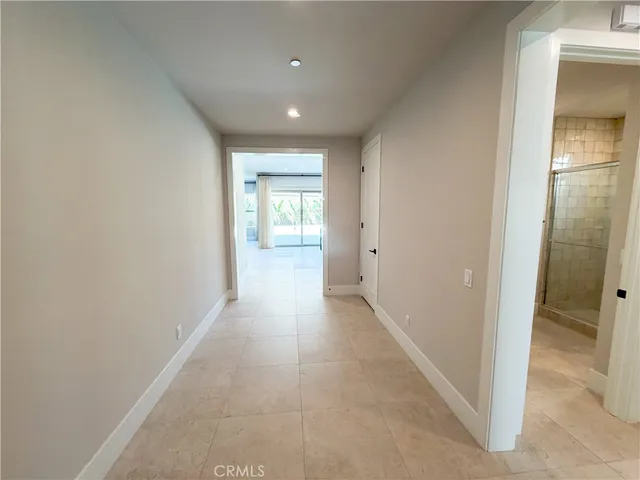 a view of a hallway with wooden floor and a bathroom