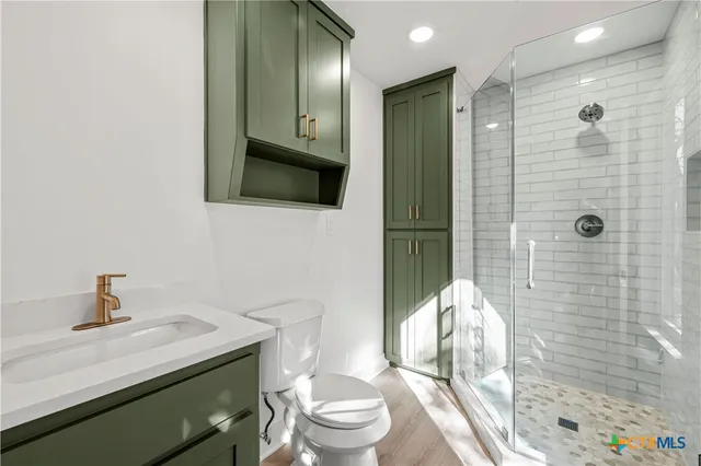 a bathroom with a sink a toilet and shower