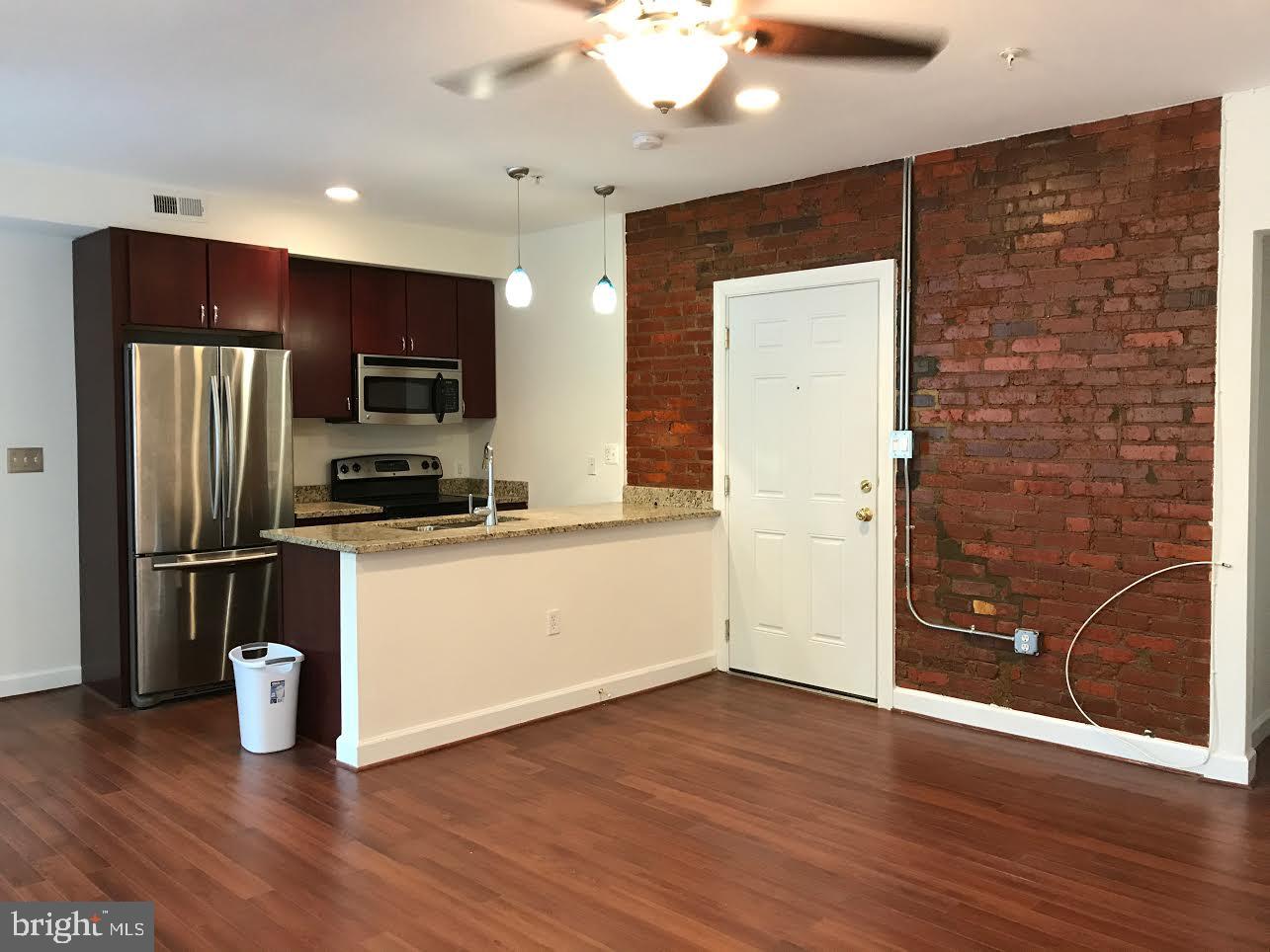 5401-5407 9th Street Northwest, Unit 102 Washington, DC 20011 - Photo 4 of 14 a kitchen with stainless steel appliances wooden floor and large cabinets
