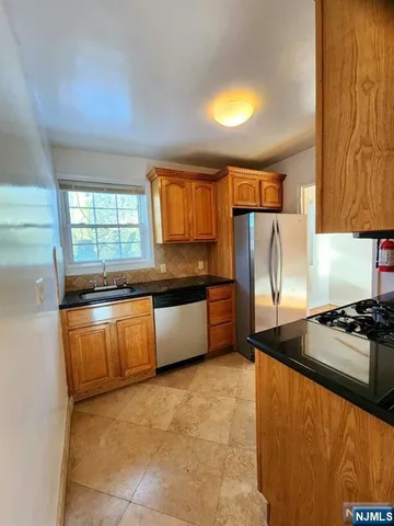 a kitchen with granite countertop a stove a sink dishwasher and a refrigerator