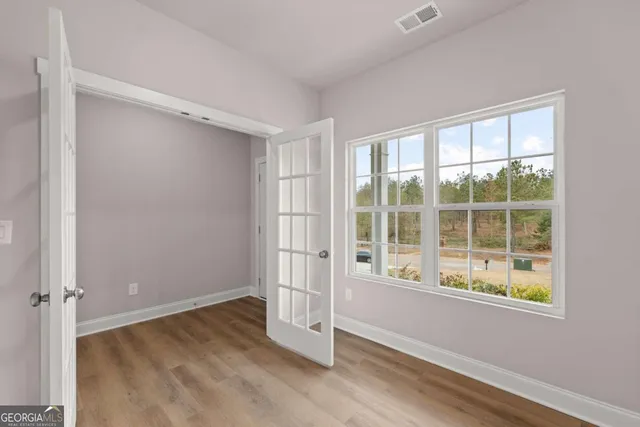 an empty room with wooden floor and windows