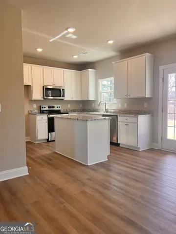 a kitchen with stainless steel appliances granite countertop a stove top oven a sink and a microwave