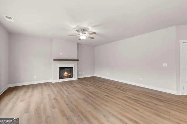 a view of an empty room with wooden floor and a fireplace