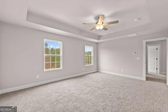 an empty room with windows and chandelier fan
