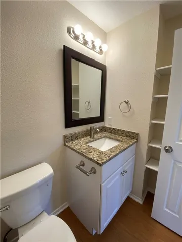 a bathroom with a granite countertop toilet sink and mirror