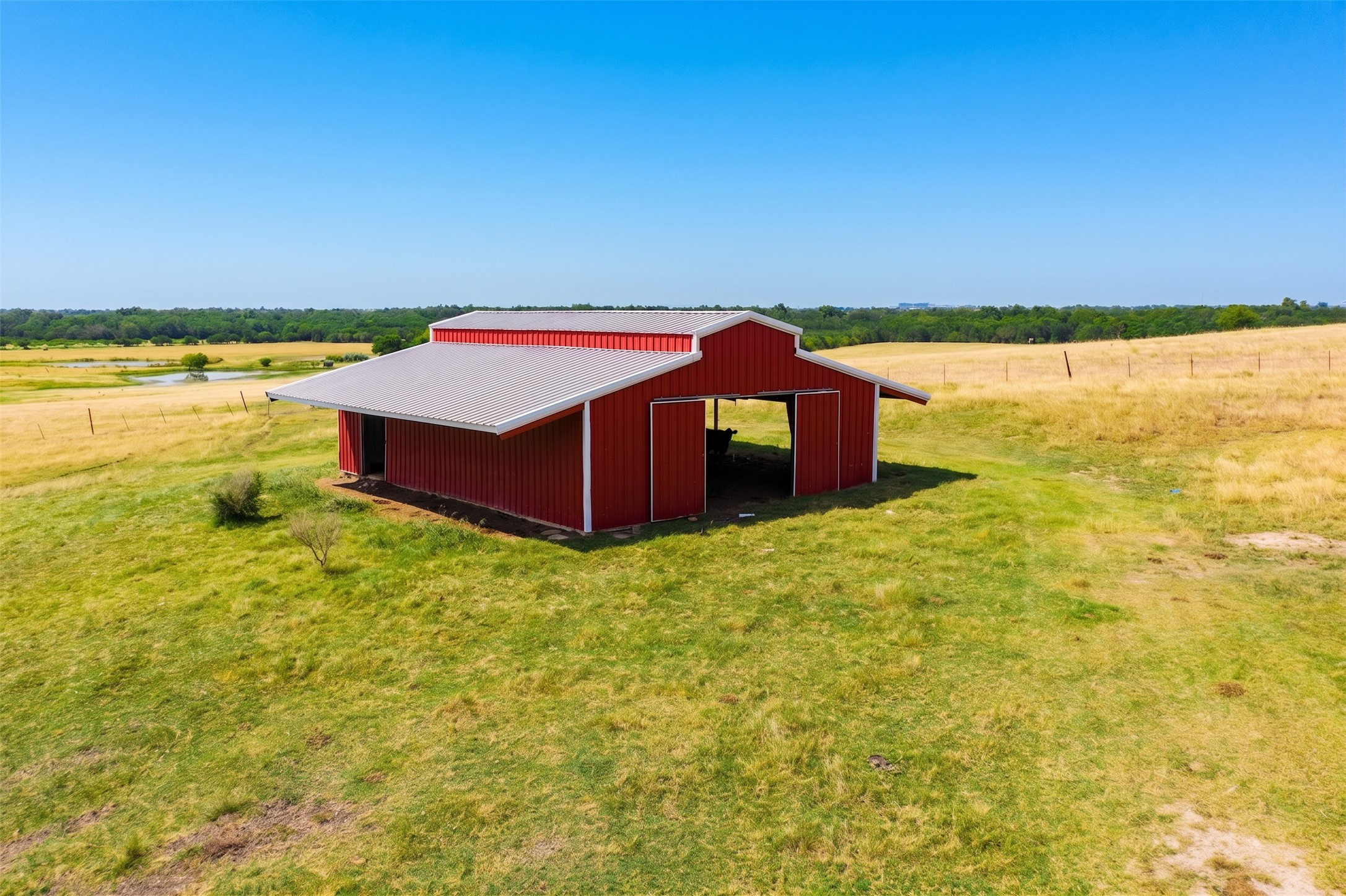 20145 Janak Road Coupland, TX 78615 - Photo 39 of 40 A vibrant red barn offers ample storage amidst verdant and golden fields, hinting at a peaceful rural lifestyle.