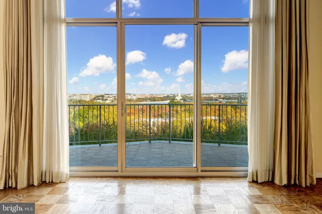 a view of a living room with a large window and wooden floor