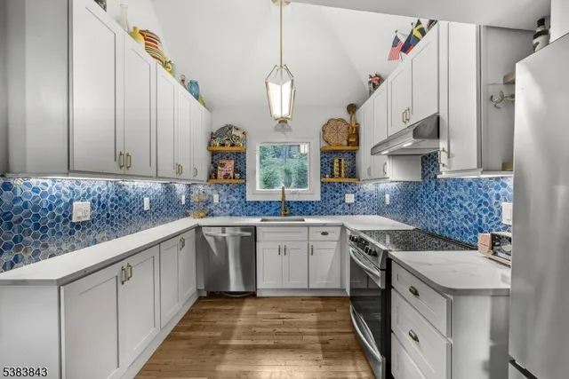 a kitchen with a sink dishwasher and white cabinets with wooden floor