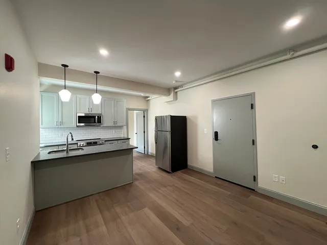 a view of kitchen with refrigerator stove and wooden floor