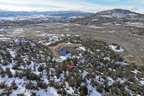 an aerial view of house with yard and mountain view in back