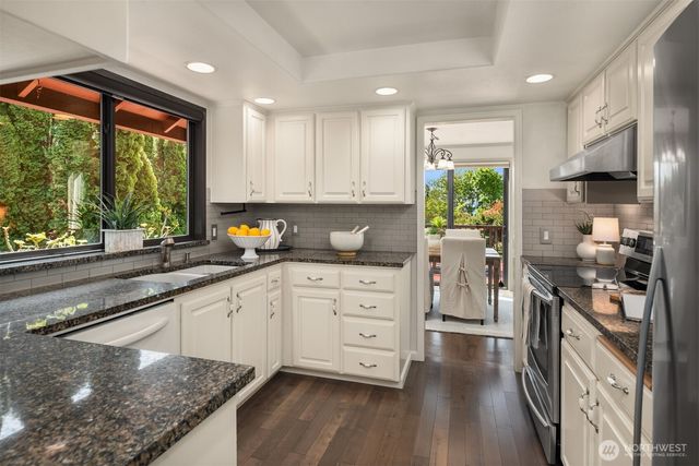 a kitchen with stainless steel appliances granite countertop a stove a sink and a granite counter tops with wooden floors
