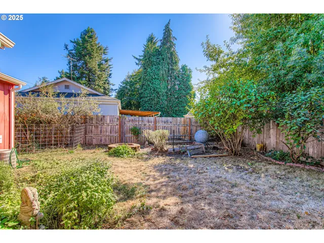 a backyard of a house with table and chairs potted plants and wooden fence